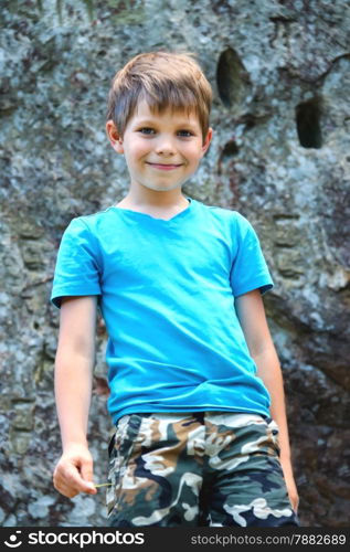 Smiling boy standing near the steep rock