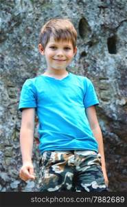Smiling boy standing near the steep rock