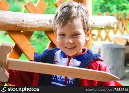 Smiling boy with a wooden sword at the playground