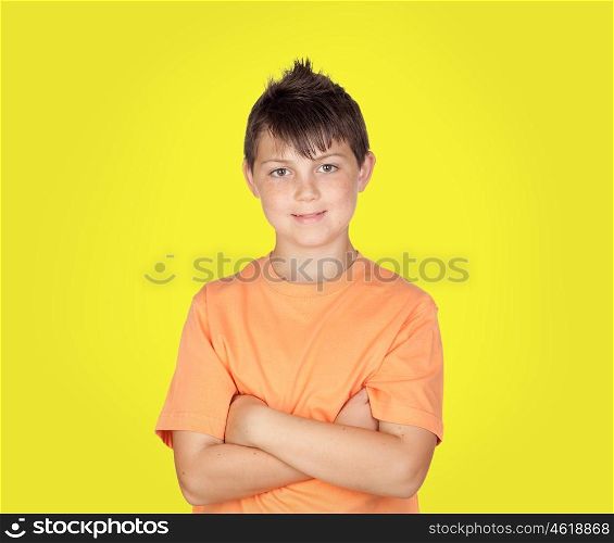 Smiling boy with arms crossed on yellow background