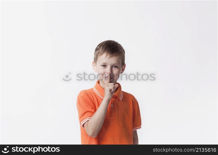 smiling boy with finger lips making silent gesture