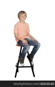 Smiling boy with orange t-shirt sitting on a stool isolated on white background