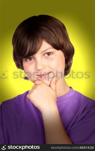 Smiling boy with the hand on his chin on yellow background