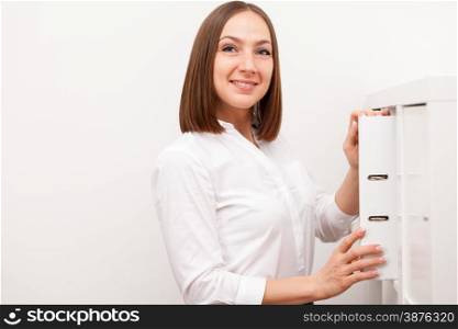 Smiling brunette businesswoman is taking the folder from the cupboard in the office