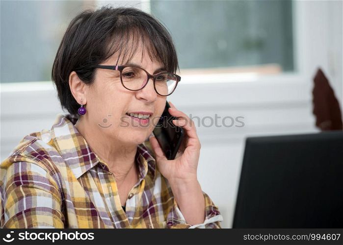 Smiling brunette senior woman using a smartphone