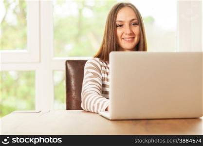 Smiling brunette woman is working with notebook at home