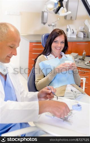 Smiling brunette woman sitting at dentist surgery chair dental clinic