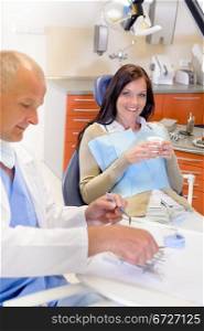 Smiling brunette woman sitting at dentist surgery chair dental clinic
