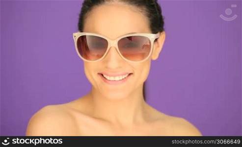 Smiling brunette woman with bare shoulders and her long hair tied back in sunglasses