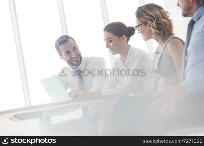 Smiling business colleagues discussing at table in new office during meeting