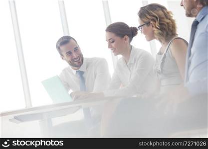 Smiling business colleagues discussing at table in new office during meeting