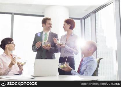 Smiling business colleagues eating lunch in boardroom during meeting at office