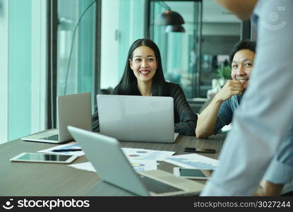 Smiling business girl using and talking to her colleagues