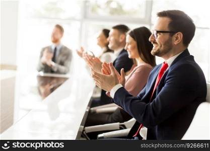 Smiling business group clapping hands at the meeting