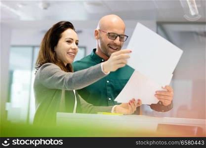 Smiling business people discussing over paperwork in office