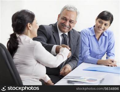 Smiling business people shaking hands in meeting