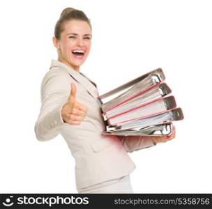 Smiling business woman holding stack of folders and showing thumbs up