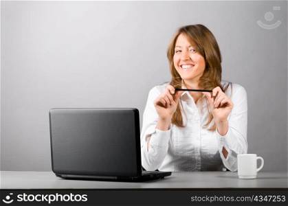 smiling business woman is sitting in the office with laptop is looking at camera