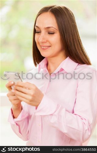 Smiling business woman is typing a message on her phone