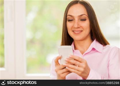 Smiling business woman is typing a message on her phone