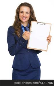 Smiling business woman pointing in blank clipboard