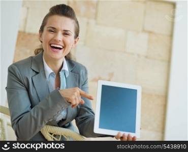 Smiling business woman pointing on tablet PC