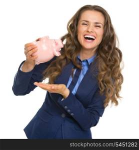 Smiling business woman shaking out coins from piggy bank