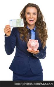 Smiling business woman showing one hundred euros and piggy bank