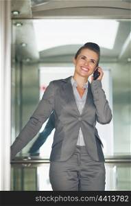 Smiling business woman talking mobile phone in elevator