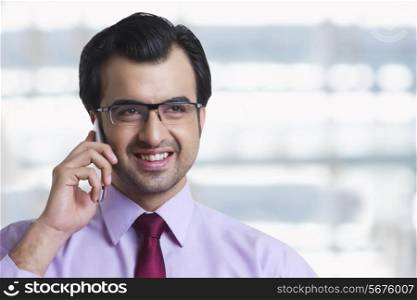 Smiling businessman answering mobile phone in office