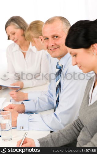 Smiling businessman behind table during meeting with team colleagues