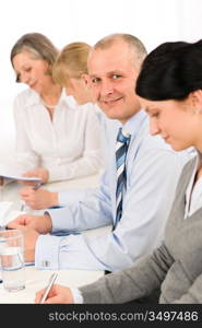 Smiling businessman behind table during meeting with team colleagues