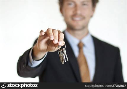 Smiling businessman handing keys to the camera