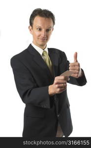 Smiling businessman handing over his businesscard while holding a thumbs up