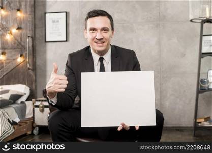 smiling businessman holding blank paper gesturing thumb up