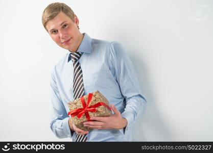 Smiling businessman holding gift box with red ribbon