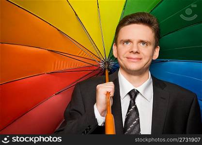 smiling businessman in suit with multi-coloured umbrella