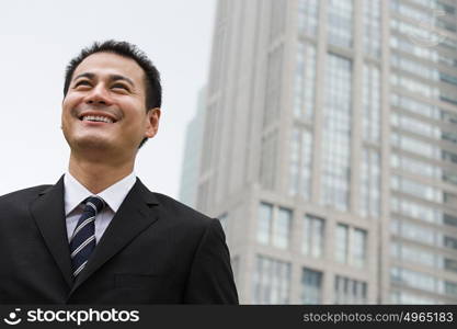 Smiling businessman near a skyscraper