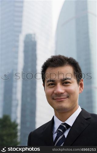 Smiling businessman near skyscrapers