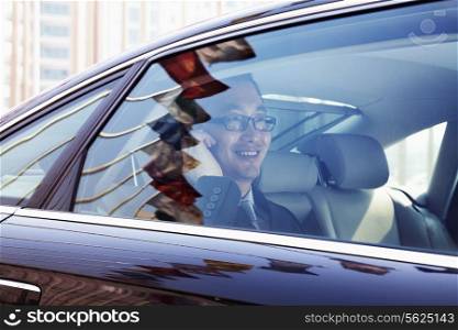 Smiling Businessman sitting in the back seat of the car