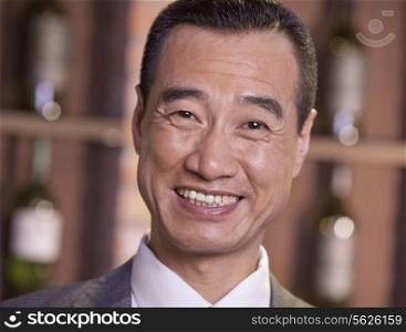 Smiling Businessman Standing by Wine Bottles, Close Up