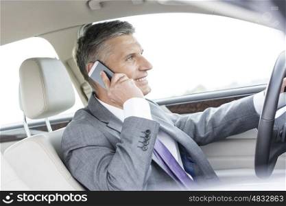 Smiling businessman talking on smartphone in car