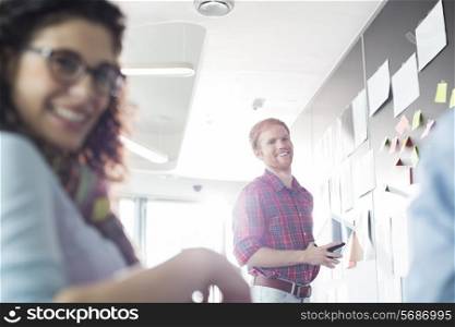 Smiling businessman with female colleague in foreground at creative office