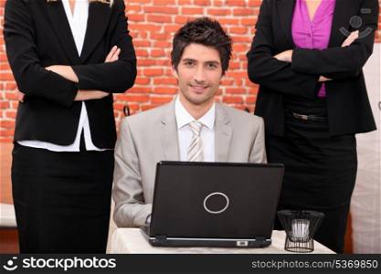 Smiling businessman with laptop surrounded by female co-workers