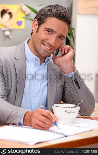 Smiling businessman working in his kitchen