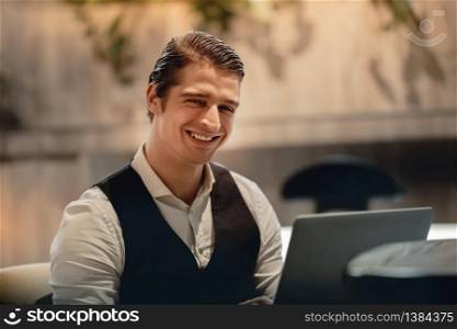 Smiling Businessman Working on Computer Laptop in Creative Working Space or Cafe. Headshot, Looking at the Camera