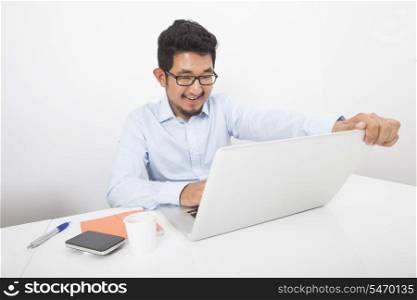 Smiling businessman working on laptop at desk in office