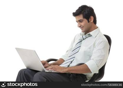 Smiling businessman working on laptop over white background