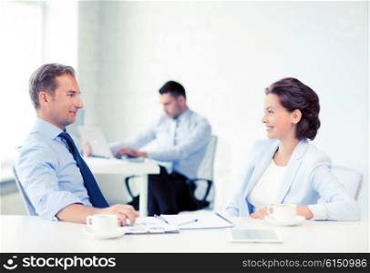 smiling businesswoman and businessman discussing something in office. man and woman discussing something in office