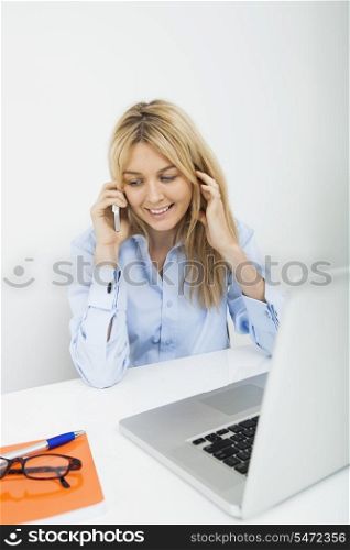 Smiling businesswoman answering cell phone in office